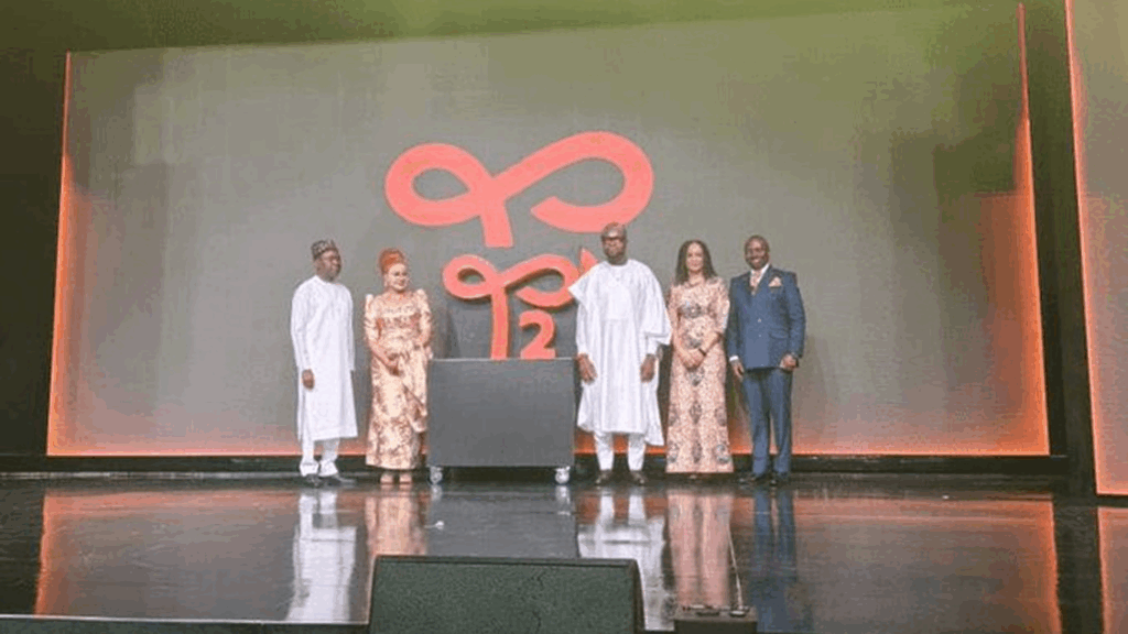Four individuals stand on a stage in front of a large screen displaying the red and black 'T2' logo, marking  9mobile's rebranding event.