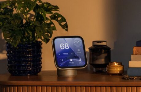 Apple HomeView smart display showing smart home controls on a wooden shelf beside a potted plant.