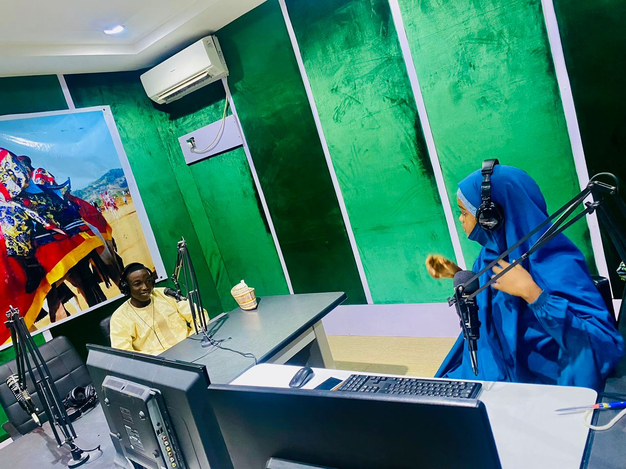 Khalifa Aliyu being interviewed on-air by a female radio host inside a brightly lit studio 